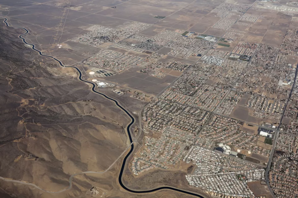 Aerial view of California Squeduct snaking past housing developments in the Mojave Desert